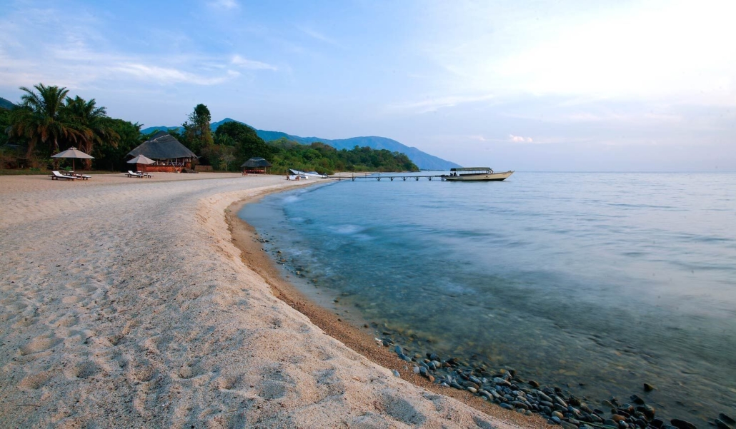 Sandy beach along Lake Tanganyika shoreline in Mahale National Park beneath forested mountain slopes
