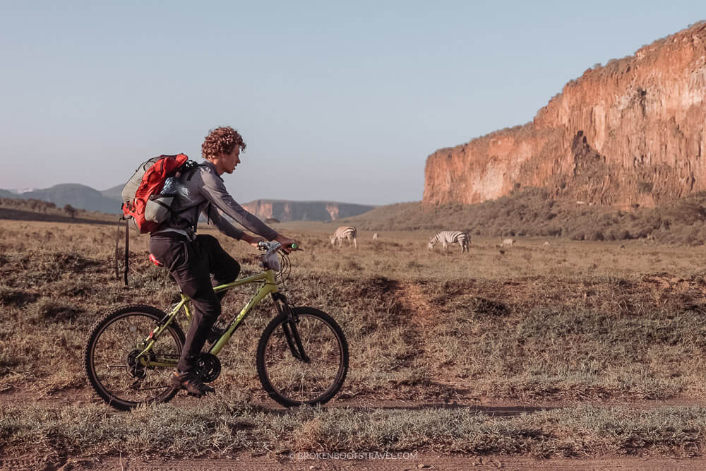 Cyclists riding through Hell's Gate National Park beside giraffes within Kenya's Rift