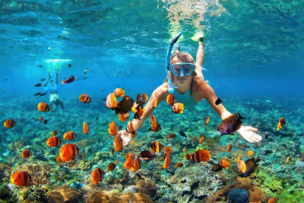 Peaceful swimmers enjoying crystal clear waters along Lake Tanganyika's scenic sandy shoreline during sunrise together