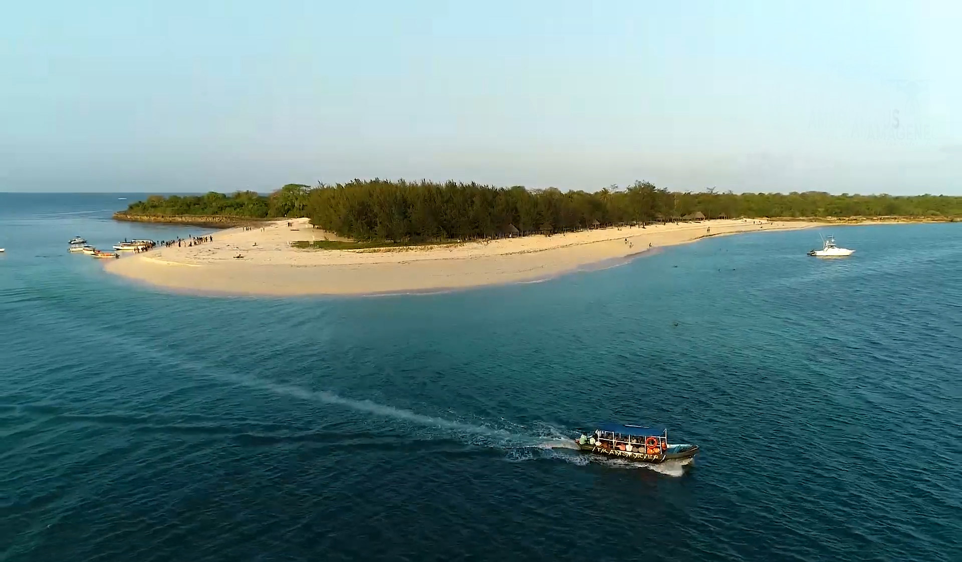Mbudya Island's white sand beach, clear turquoise water, and shaded thatched bandas.