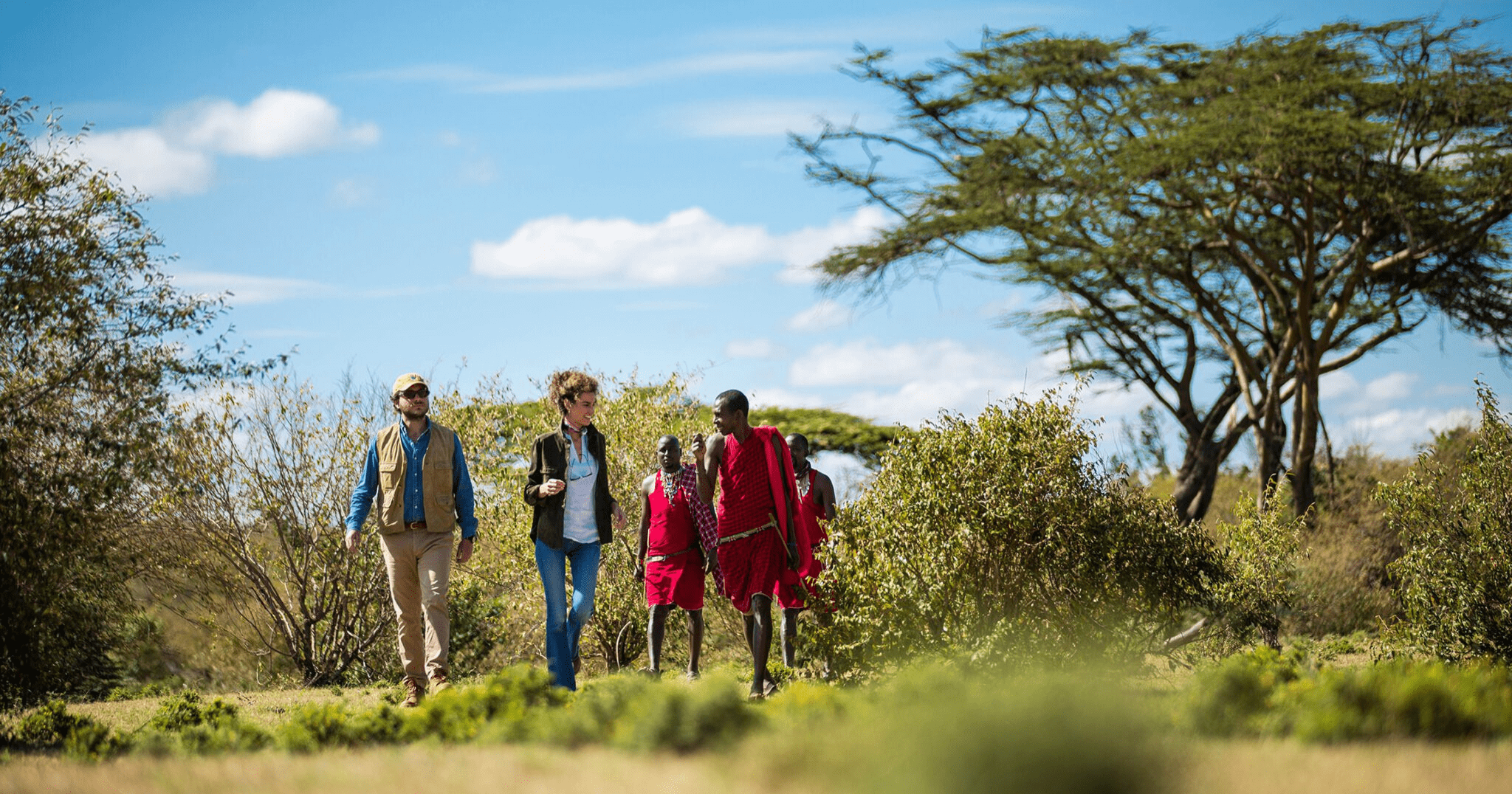 Maasai guide leading tourists on cultural walking safari through Naboisho Conservancy grasslands