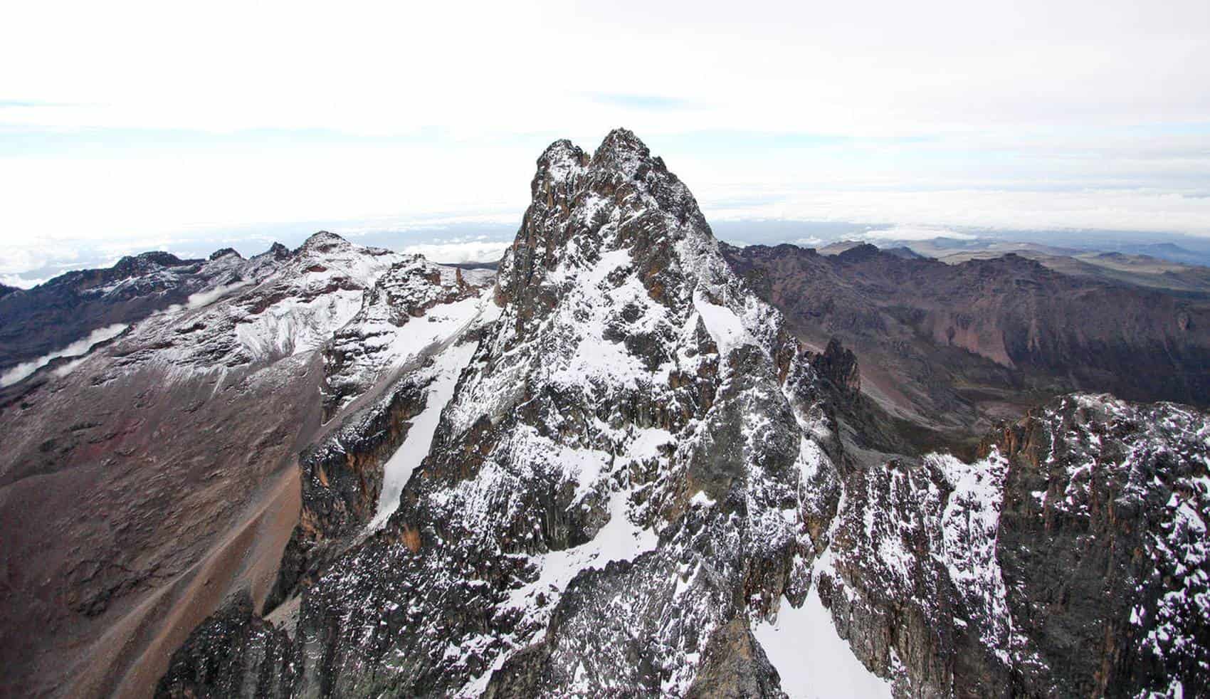 Snow-capped Mount Kenya overlooking alpine lakes, giant lobelias, and dramatic rocky peaks under sunrise skies.