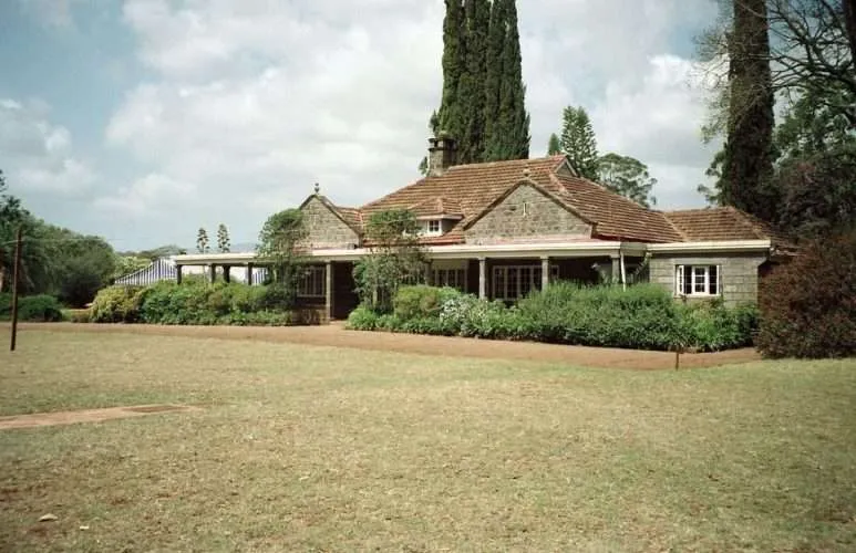 Karen Blixen Museum farmhouse interior showcases vintage furniture, writing desk, and colonial-era photographs displayed.
