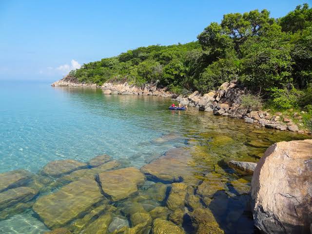Crystal clear Lake Tanganyika shoreline with colorful fish visible beneath calm freshwater surface today