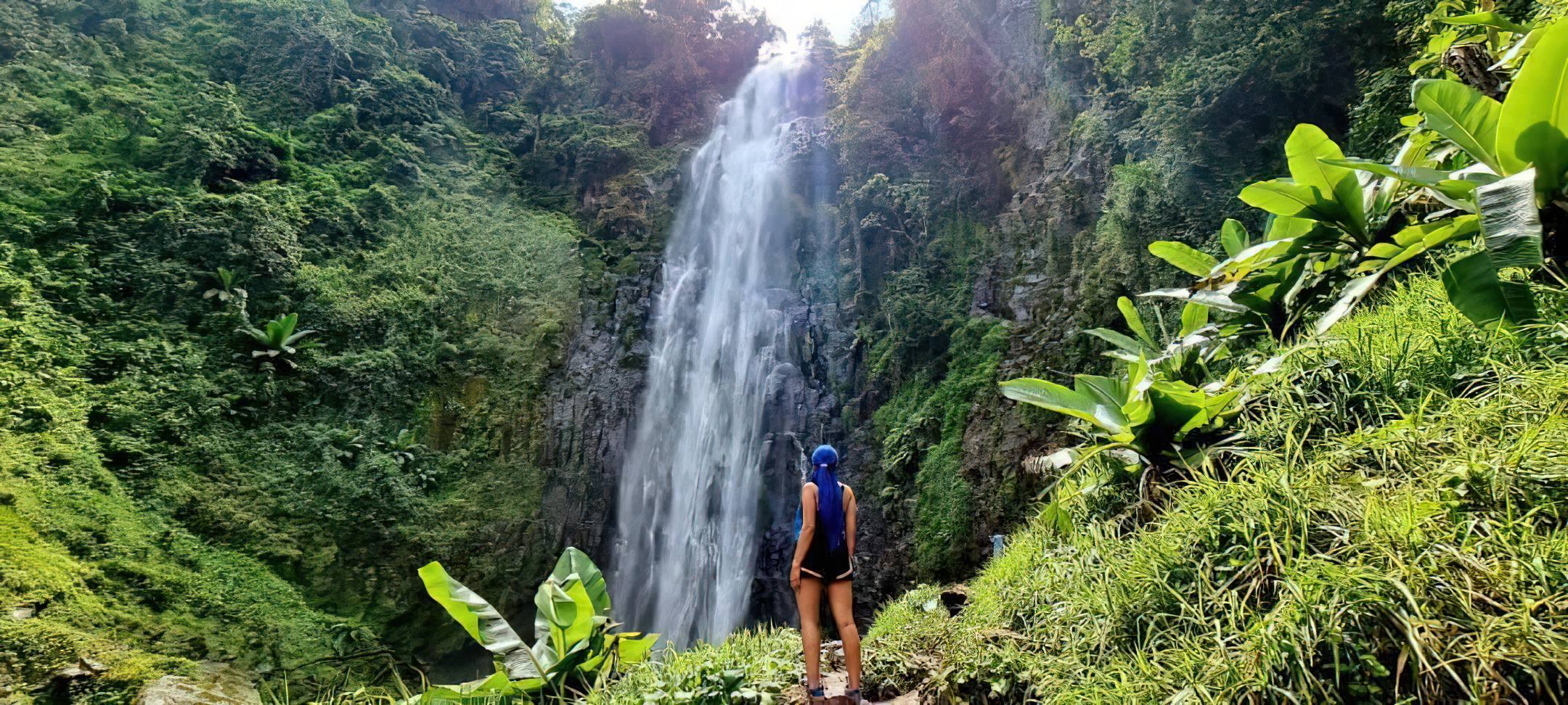 Visitors enjoying Materuni Waterfalls surrounded by lush forest and cascading mountain streams in Tanzania.