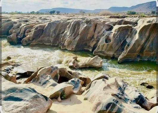 Scenic rock formations surrounding flowing rapids along Galana River within Tsavo East National Park